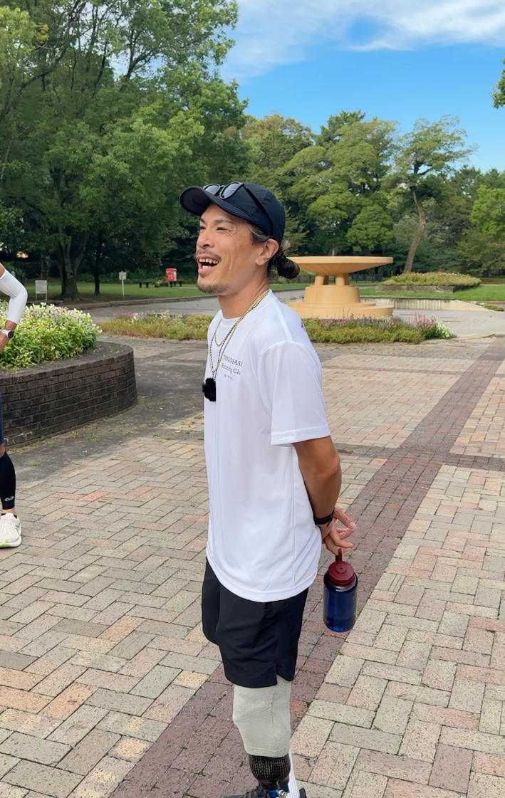 公園で白いTシャツを着て笑顔を見せる主催者